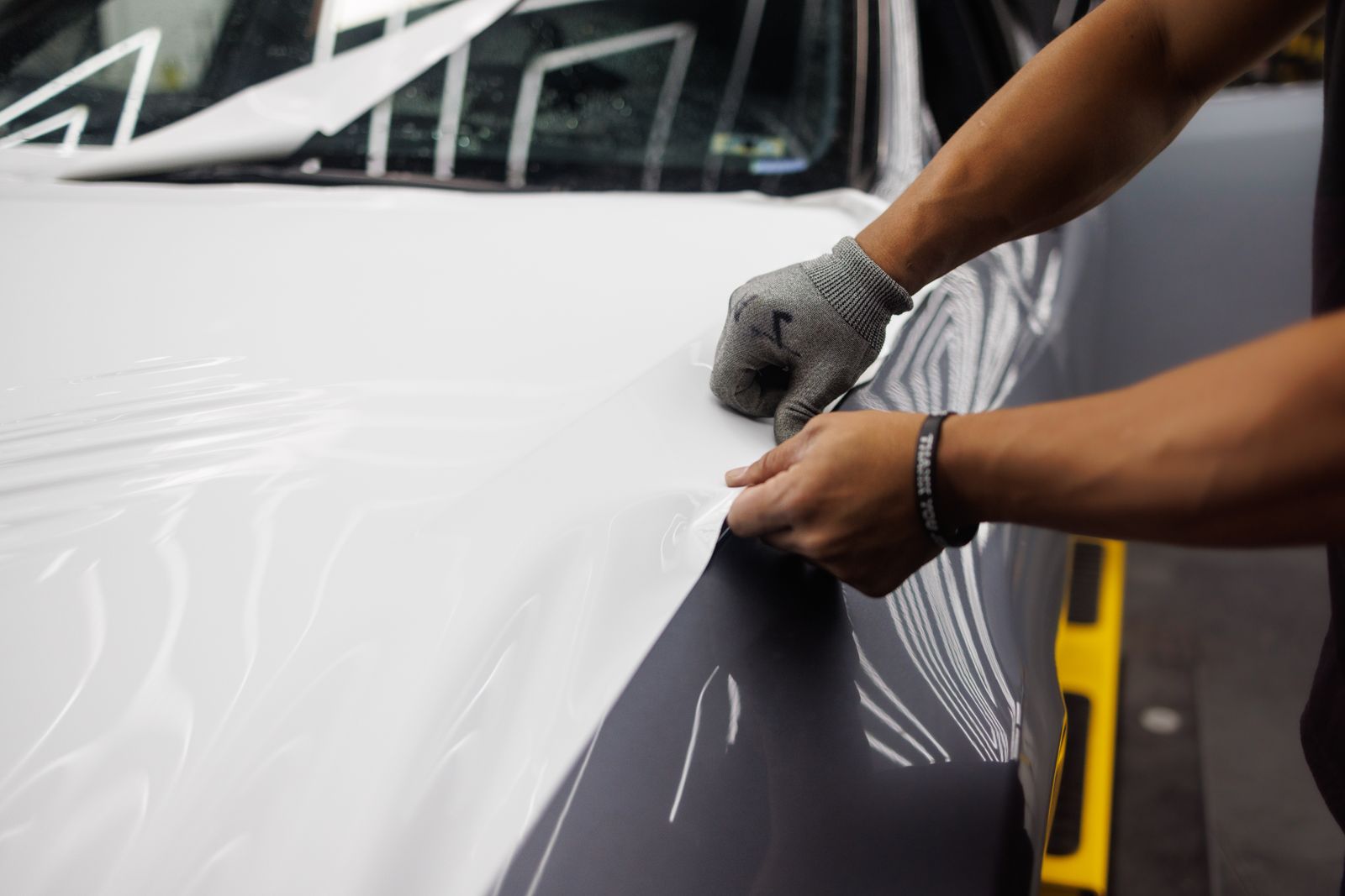 Close-up of hands applying film to a hood