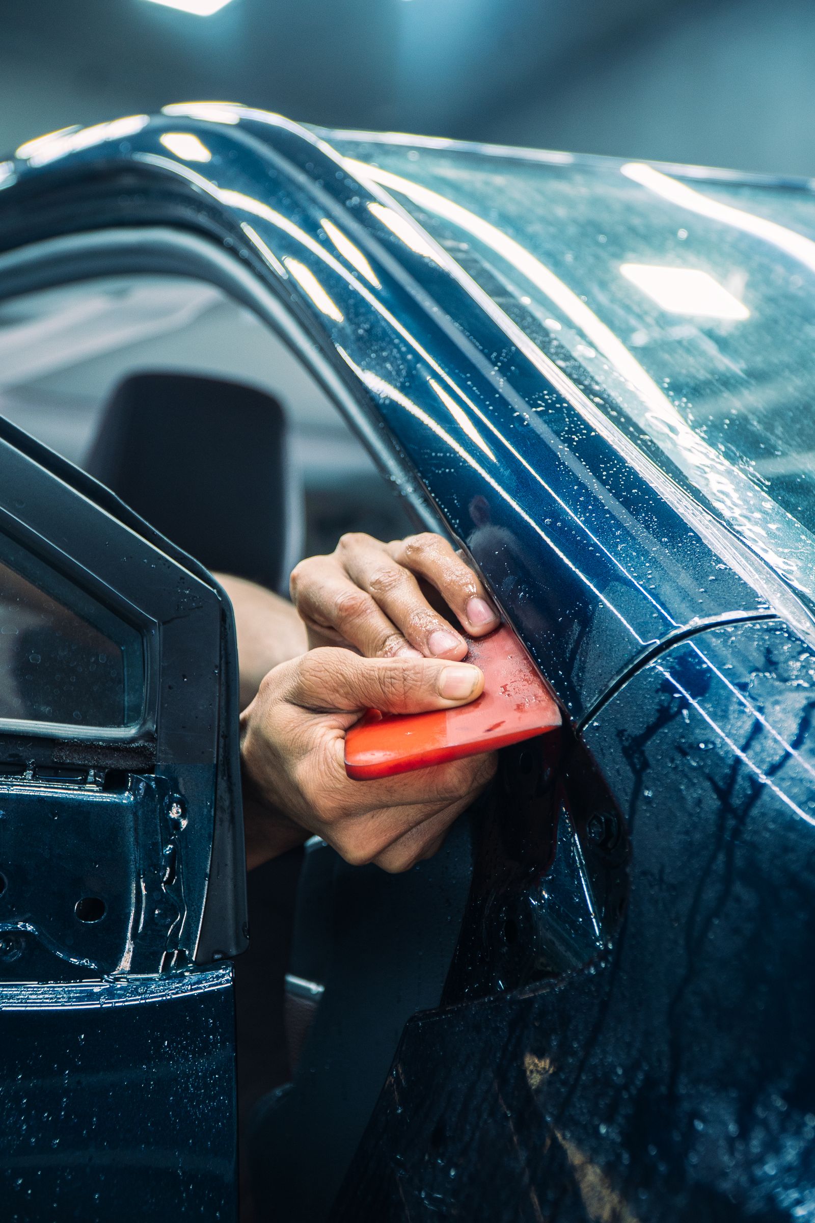 Installer squeegeeing paint protection film onto a car door